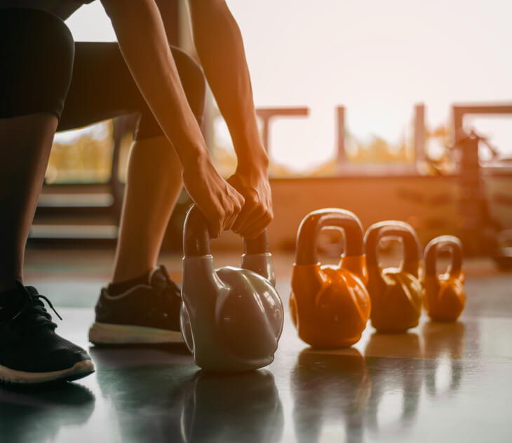 person picking up a kettlebell at the gym.